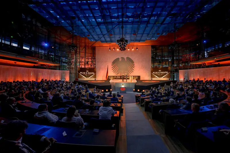 Blick in den vollbesetzten Saal der Plus X Award Night, vorn die Bühne unter dem Bundesadler