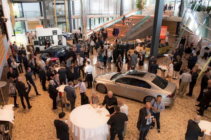 Empfang im Foyer der Plus X Award Night mit Gästen an Stehtischen und ausgestellten Autos
