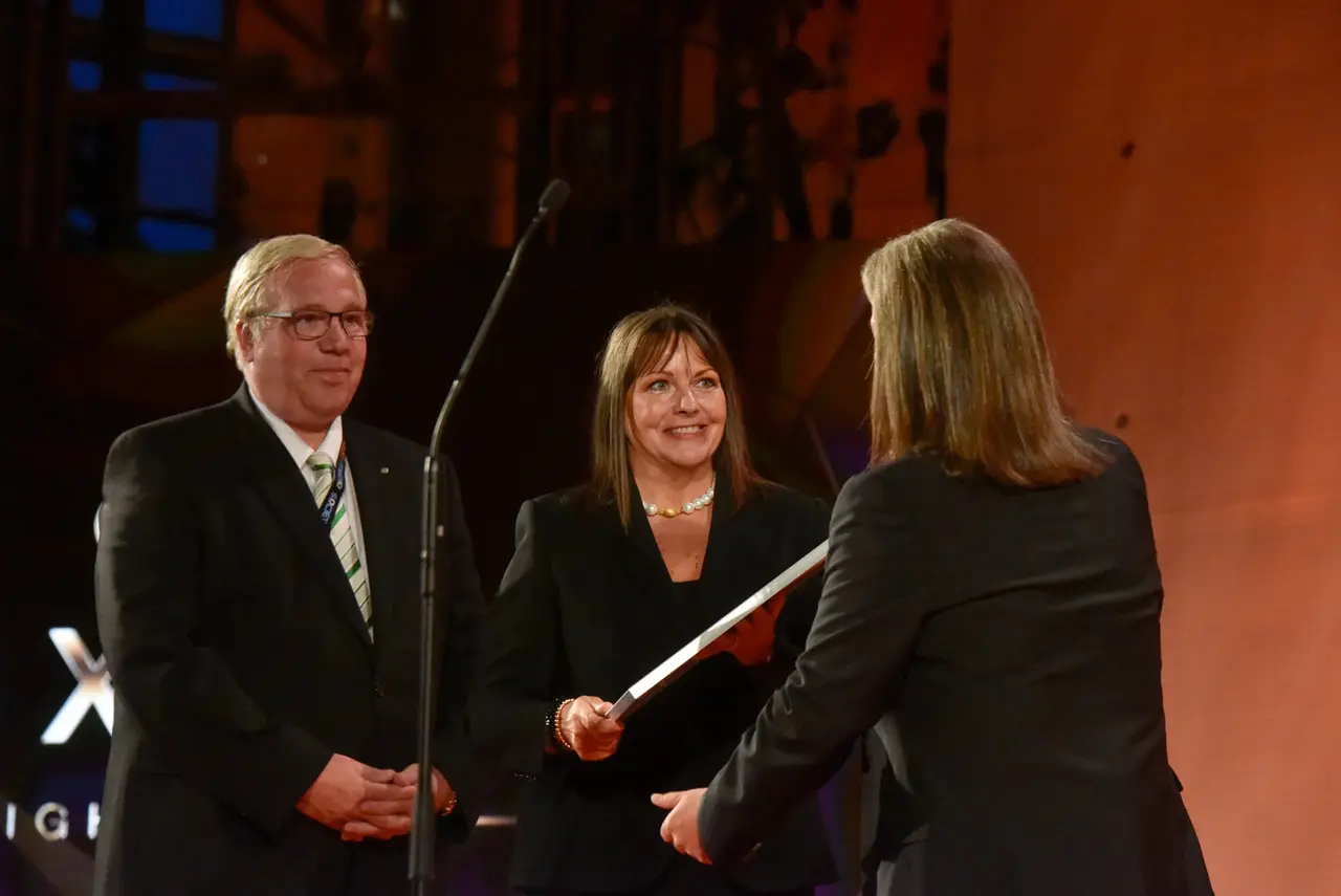 Preisträger nehmen auf der Bühne der Plus X Award Night eine Urkunde entgegen