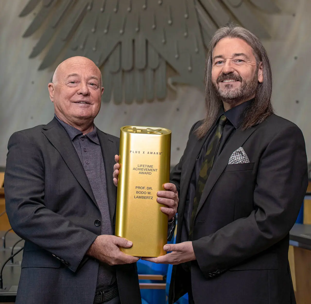 Prof. Dr. Bodo W. Lambertz mit der goldenen Trophäe für das Lebenswerk vor dem Bundesadler