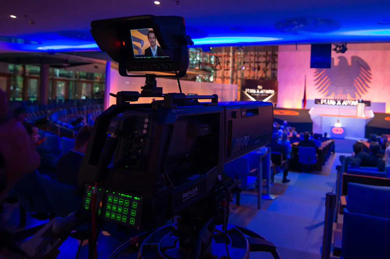 Fernsehkamera zeichnet die Plus X Award Night auf, im Hintergrund die Bühne unter dem Bundesadler