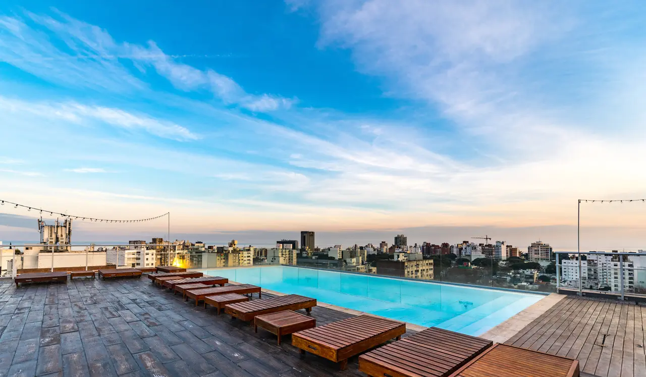 Dachterrasse mit Pool und Sonnenliegen über den Dächern einer Stadt