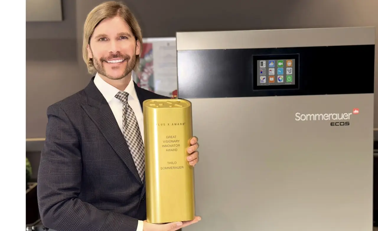 Thilo Sommerauer mit der Trophäe „Great Visionary Innovator Award“ vor einer Sommerauer-ECOS-Heizung