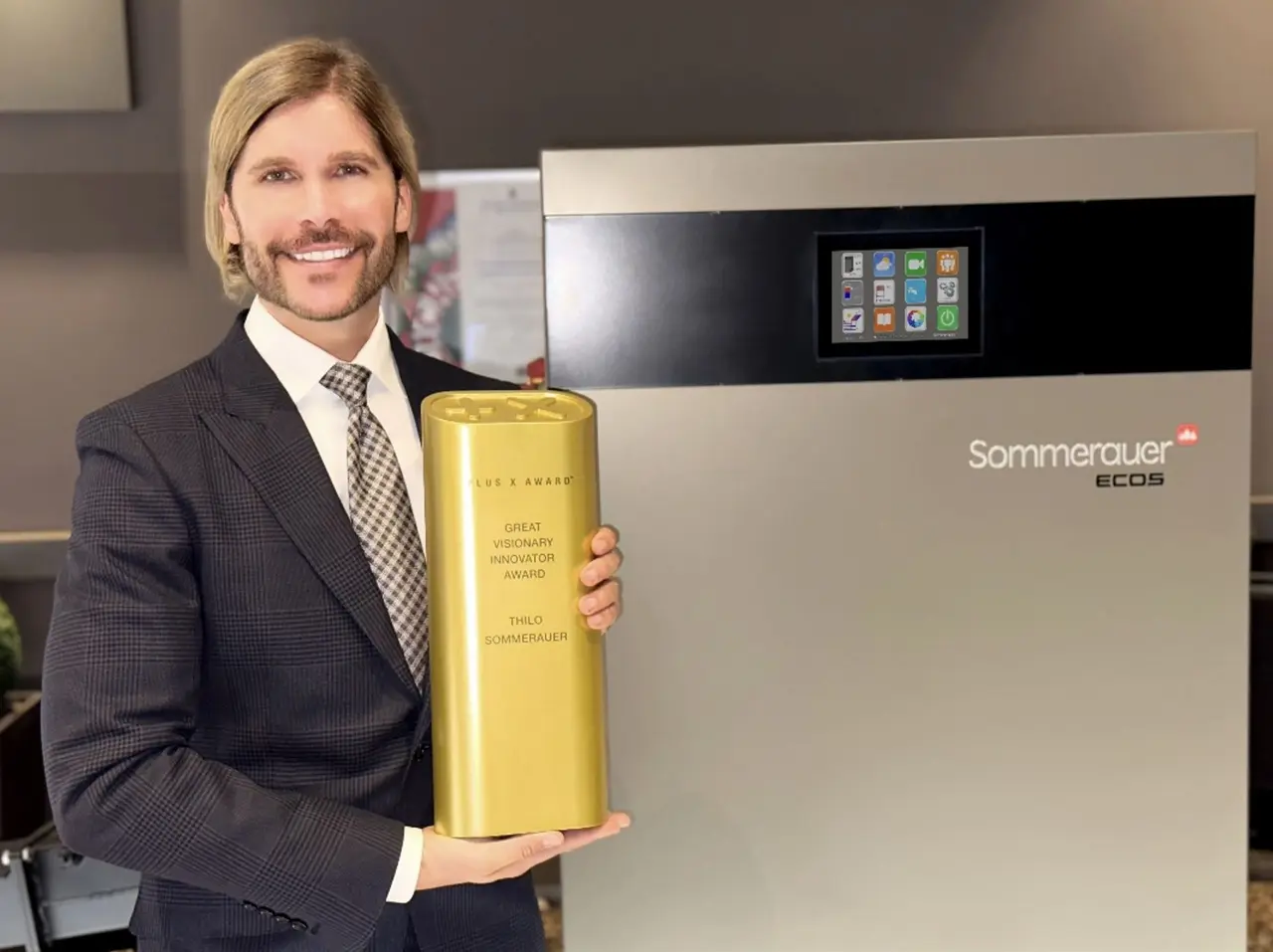 Thilo Sommerauer mit der Trophäe „Great Visionary Innovator Award“ vor einer Sommerauer-ECOS-Heizanlage